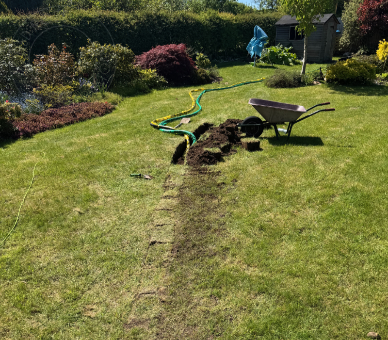 Starting to make some progress with the trench, while sweating like a pig. Cut turf, lift turf, dig hole, bury duct, replace turf. Repeat.